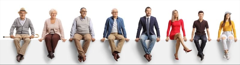 Several people facing forward while sitting on a white ledge against a white background